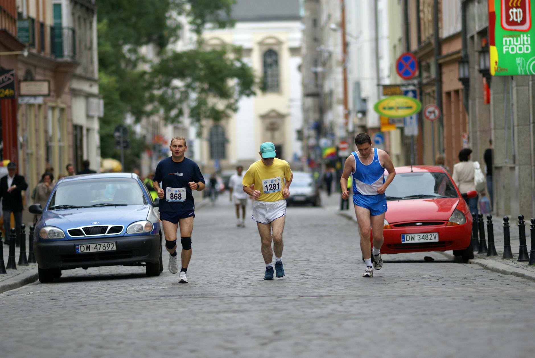 Uczestnicy biegnący ulicą w Łodzi podczas wydarzenia sportowego, biegacze, miasto Łódź